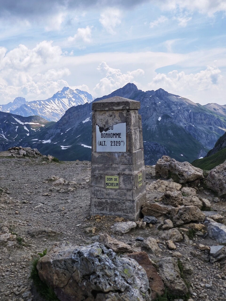 Der Grenzstein am Col du Bonhomme auf 2.329 m, mit schneebedeckten Graten in den Wolken
